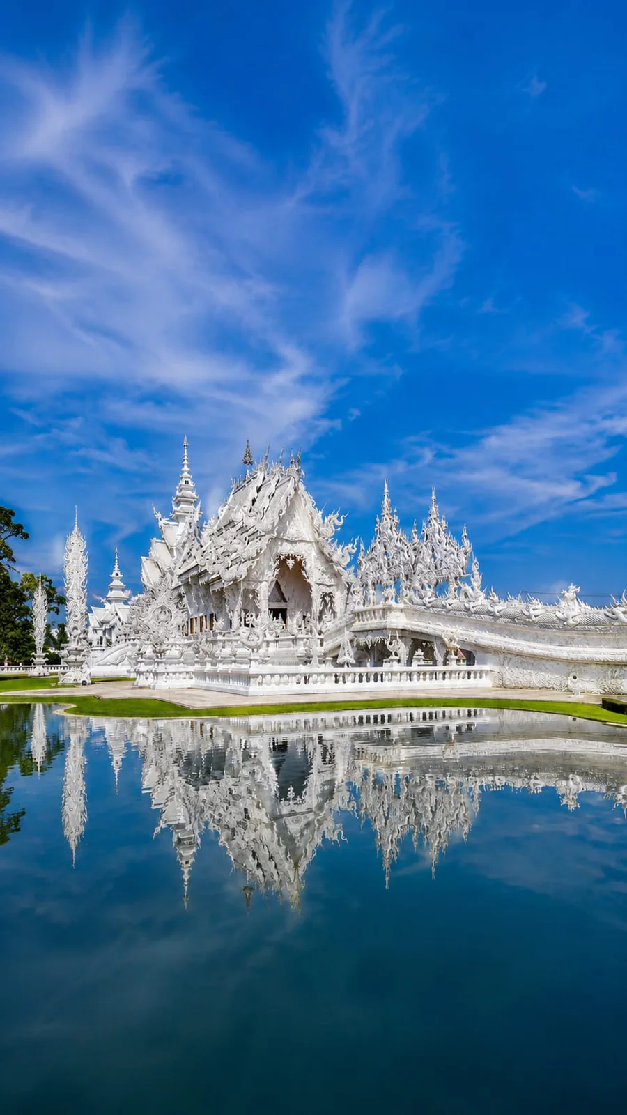 Templo Blanco de Chiang Rai reflejado sobre el agua bajo el cielo azul
